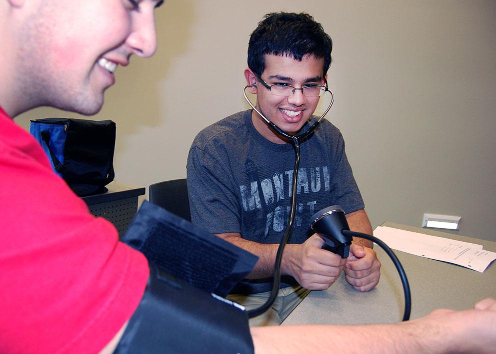 Two camp students practice checking blood pressure
